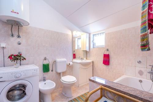 a bathroom with a toilet a sink and a washing machine at Ferienwohnung in bester Lage, nahe dem Meer in Barbariga