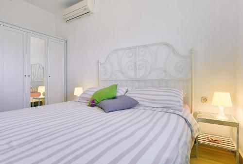 a white bedroom with a large bed with purple and green pillows at Appartement Tiffany in Ližnjan