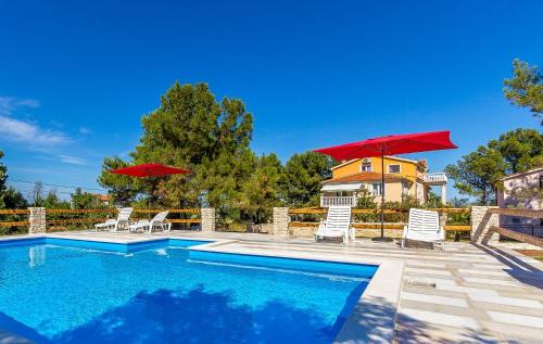 een zwembad met stoelen en parasols en een huis bij Ferienwohnung mit großem Pool nur 500 Meter bis zum Kieselstrand mit Klima, WLAN, Terrasse, Grillplatz in Ližnjan