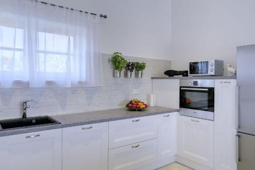 a white kitchen with a sink and a microwave at Schöne Finca mit privatem Pool, Klima, WLAN, Terrasse, Grill in Kavran