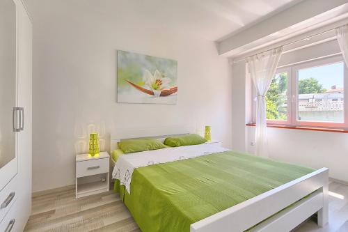 a white bedroom with a green bed and a window at Im Jahr 2014 renoviertes Ferienhaus 400 Meter zum Strand in Premantura