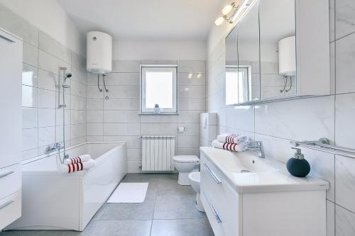 een witte badkamer met een wastafel en een toilet bij Appartement mit großem Garten und Grillbereich in Valtura