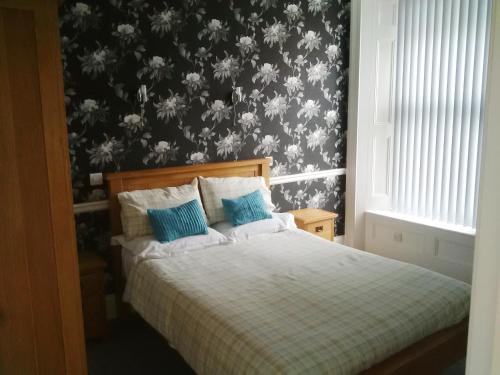 Schlafzimmer mit einem Bett mit einer schwarz-weißen Tapete in der Unterkunft Glenholme Apartments in Tenby