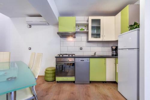 a kitchen with green and white cabinets and a table at Wunderschöne Villa mit privatem Pool, Klima, WLAN in Valtura
