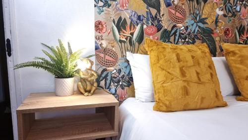 a bed with a yellow pillow and a table with a plant at 3 bed flat O2 arena Dyson house in London