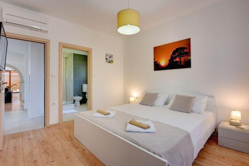 a bedroom with a large white bed with two towels on it at Villa nur 800 Meter zum Strand mit Meerblick, privatem Pool, BBQ und Spielplatz in Fažana