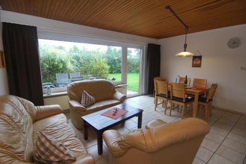 ein Wohnzimmer mit Sofas, einem Tisch und einem Esszimmer in der Unterkunft Bungalow Tilla in Norddeich