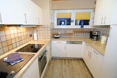 a small kitchen with white cabinets and wooden floors at Bungalow Windsbraut in Norddeich