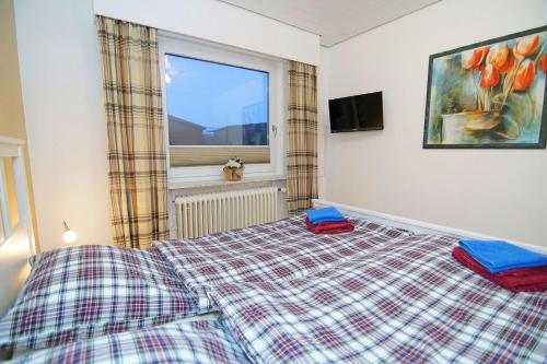 a bedroom with a bed and a window at Bungalow Windsbraut in Norddeich