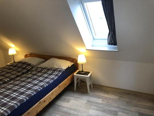 1 dormitorio con 1 cama con ventana y 2 lámparas en Fewo Imke en Norden