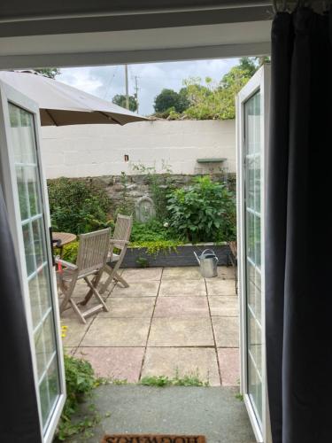 an open door to a patio with two chairs at Bryntirion Farmhouse Apartment with Hot Tub in Llanfair Caereinion