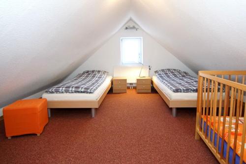 ノルトダイヒにあるHaus Anneのベッド2台と窓が備わる屋根裏部屋です。