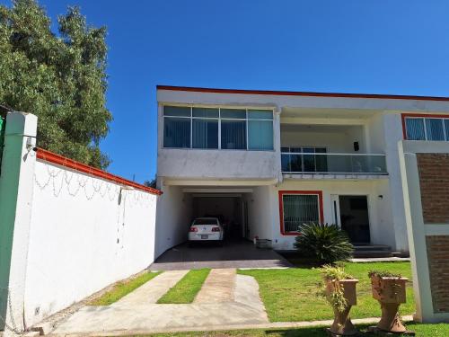 a white house with a car parked in the driveway at Xochimilco Hermoso Departamento Loft junto a Trajineras in Mexico City