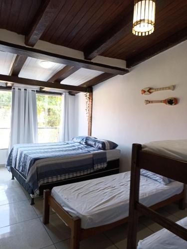 a bedroom with two beds and a window at Pousada Portal da Mucugê in Porto Seguro