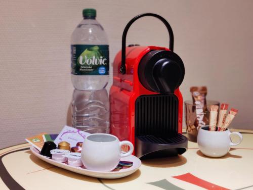 a coffee maker and a cup and a bottle of water at Spacious & comfortable guestrooms w private bathrooms near Koelnmesse & Lanxess Arena, free parking, highspeed WiFi in Cologne