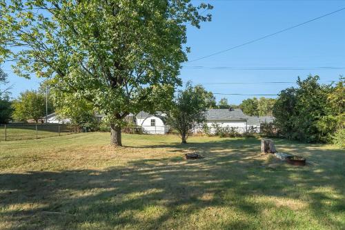 a tree in a yard with a house in the background at The Kentucky Bluegrass Retreat in Frankfort
