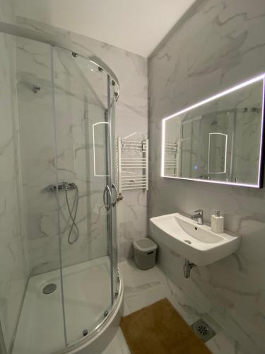a white bathroom with a shower and a sink at Mona in Banja Luka