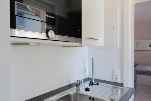 eine Küche mit einer Spüle und einer Mikrowelle in der Unterkunft Ferienwohnung 3 Haus Meeresrauschen - Bungalow in Haffkrug