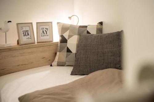 uma cama com duas fotografias e uma almofada em Traumhafter Ostsee-Ausblick, FeWo direkt am Strand em Fehmarn