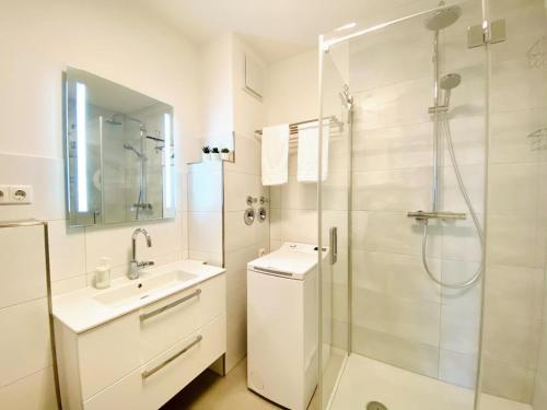 uma casa de banho branca com um chuveiro e um lavatório. em Traumhafter Ostsee-Ausblick, FeWo direkt am Strand em Fehmarn