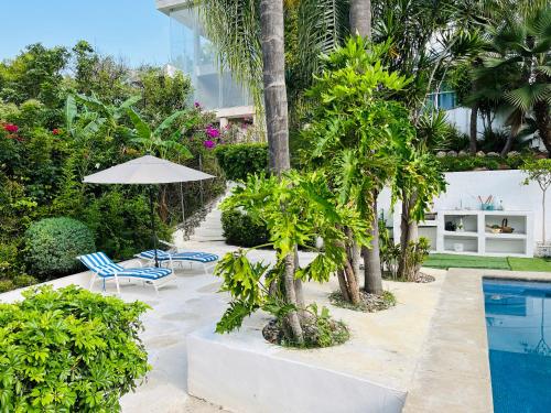 una piscina con 2 sillas, sombrilla y árboles en Casa en Residencial San Gaspar, en Jiutepec