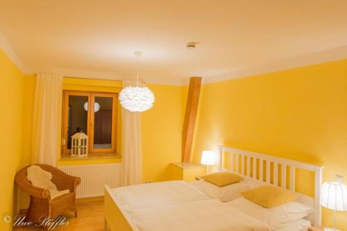 a yellow bedroom with a bed and a chair at Ferienwohnung Maierers Schaiere in Gammesfeld