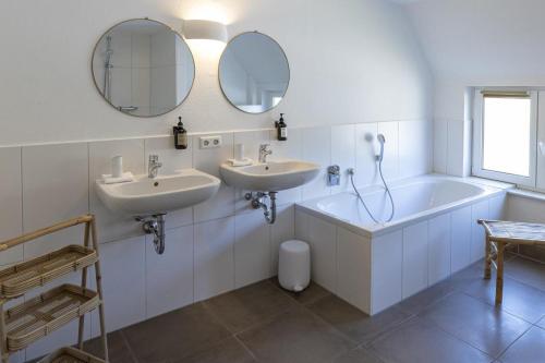 a bathroom with two sinks and a tub and mirror at Ferienhaus Pure Jagst, Traum-Lage am Fluss mit Kaminzimmer und Infrarot-Wärmekabine 
