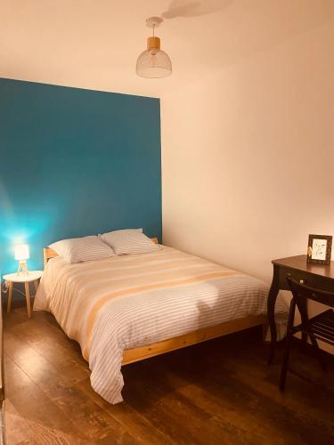 un lit dans une chambre avec un mur bleu dans l'établissement Au porte du château, à Chinon