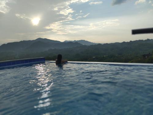 a woman sitting in a infinity pool looking at the mountains at Cristal Tayrona in Los Naranjos