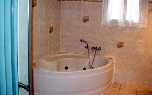 een wit bad in een badkamer met een raam bij Maison de 4 chambres avec vue sur la ville jacuzzi et jardin clos a Castelnau Montratier in Castelnau-de-Montratier