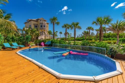 a large swimming pool with a wooden deck and a house at Bella Vista in Fort Pierce