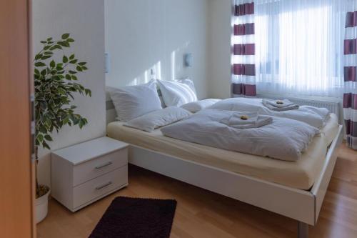 ein Bett mit weißer Bettwäsche und einer Pflanze in einem Zimmer in der Unterkunft Ferienwohnung 3 Am Petersberg in Neef