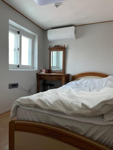 a bedroom with a bed and a desk with a mirror at Clara House in Seoul