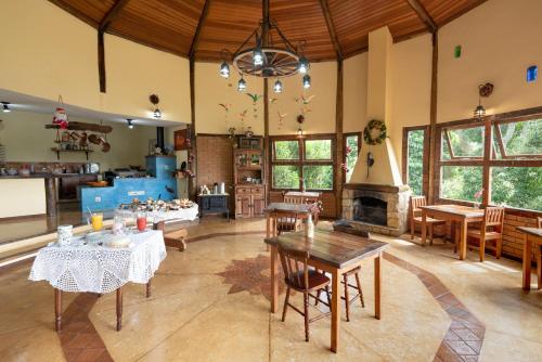 uma grande sala de estar com mesas e uma lareira em Pousada Serra Vista em Gonçalves