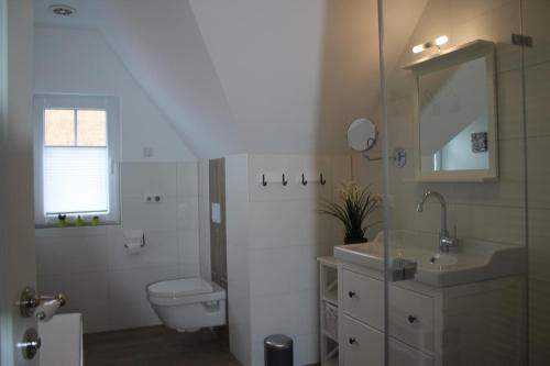 a white bathroom with a toilet and a sink at Ferienwohnung Morgensonne in Born