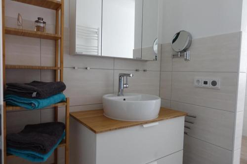 a white bathroom with a sink and towels at Ferienwohnung de Windroos in Born
