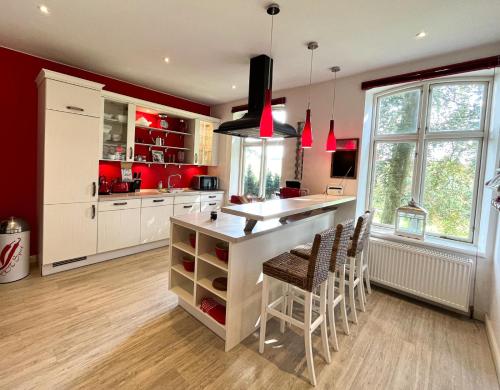a kitchen with red walls and a white island with chairs at Ferienhaus NATURlich Wassermuhle in Kappeln