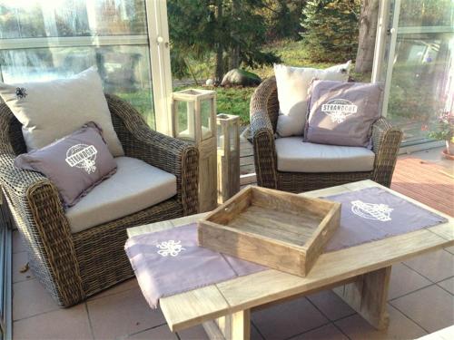 a patio with wicker chairs and a coffee table with a tray at Ferienhaus NATURlich Wassermuhle in Kappeln
