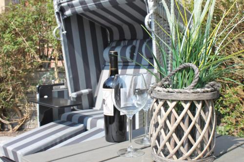 a bottle of wine and a wine glass on a bench at Strandkorb in Kappeln