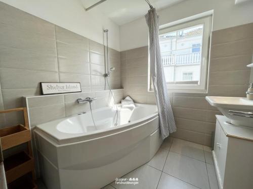 a white bathroom with a tub and a sink at The Sea Room in Olpenitz