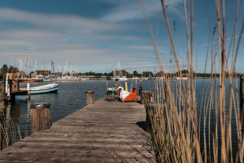a person sitting on a dock with a table and a boat at Altes Kapitänshaus in Arnis