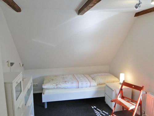 Un dormitorio con una cama blanca y una silla roja. en Skrey's To Hus, en Kappeln