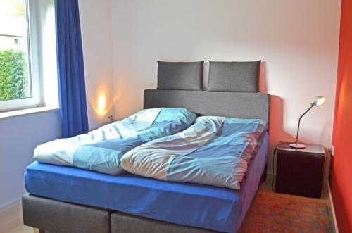 Bett mit blauer Decke in einem Zimmer in der Unterkunft Schleiglanz in Ulsnis