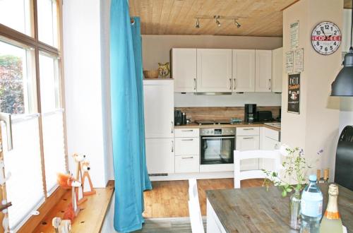 uma cozinha com armários brancos e uma mesa de madeira em Pippilotta em Kronsgaard
