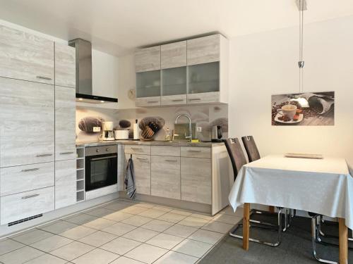 a kitchen with white cabinets and a dining table at Strandgold in Kronsgaard