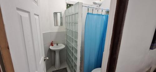 a bathroom with a blue shower curtain and a sink at Layback Surf Hotel in Tamanique