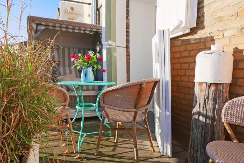 a patio with chairs and a table with a vase of flowers at Hafenheimat in Kappeln