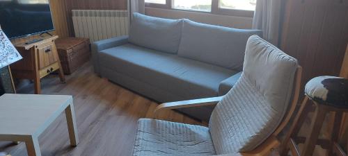 uma sala de estar com um sofá e uma televisão em Peña del viento a pie de pistas estación San Isidro em Puebla de Lillo