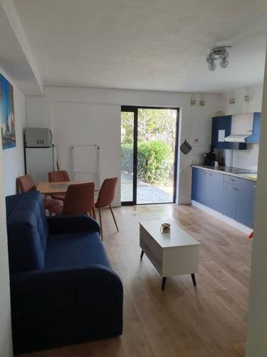 un salon avec un canapé bleu et une table dans l'établissement Studio équipé et meublé St Cyprien, à Saint-Cyprien