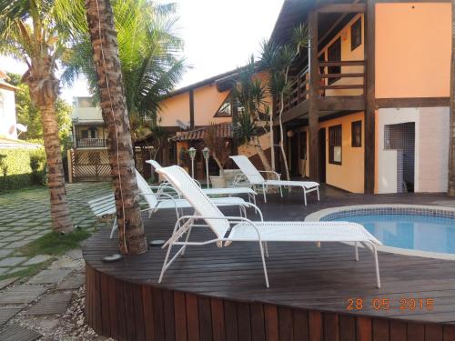eine Terrasse mit weißen Stühlen und einem Pool in der Unterkunft Solar da Praia Pousada in Arraial do Cabo